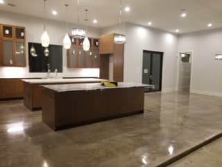 Spacious modern kitchen featuring two large islands, polished reflective floors, and elegant pendant lighting.
