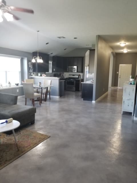 Open-concept living room and kitchen with polished grey concrete floors and dark cabinetry.
